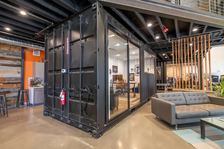Black shipping container converted into a private office with full-height glass sliding doors