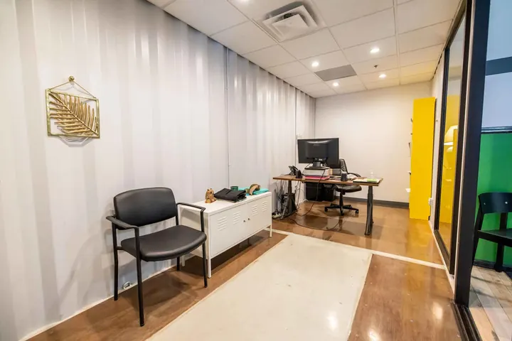 Container private office interior with painted corrugated walls, drop ceiling with recessed lights and polished floors