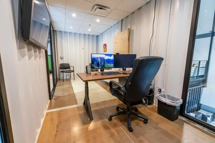 Container office with standing desk, dual monitors and wall-mounted display