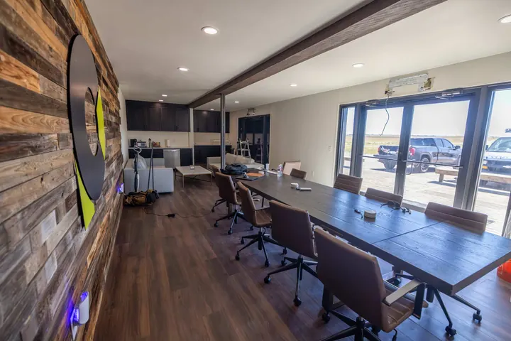 Container office conference room with reclaimed wood accent wall, long table and glass doors to a deck