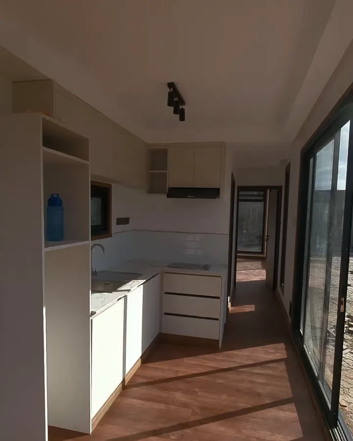 Container conversion kitchen with white cabinets, sink and wood-look flooring