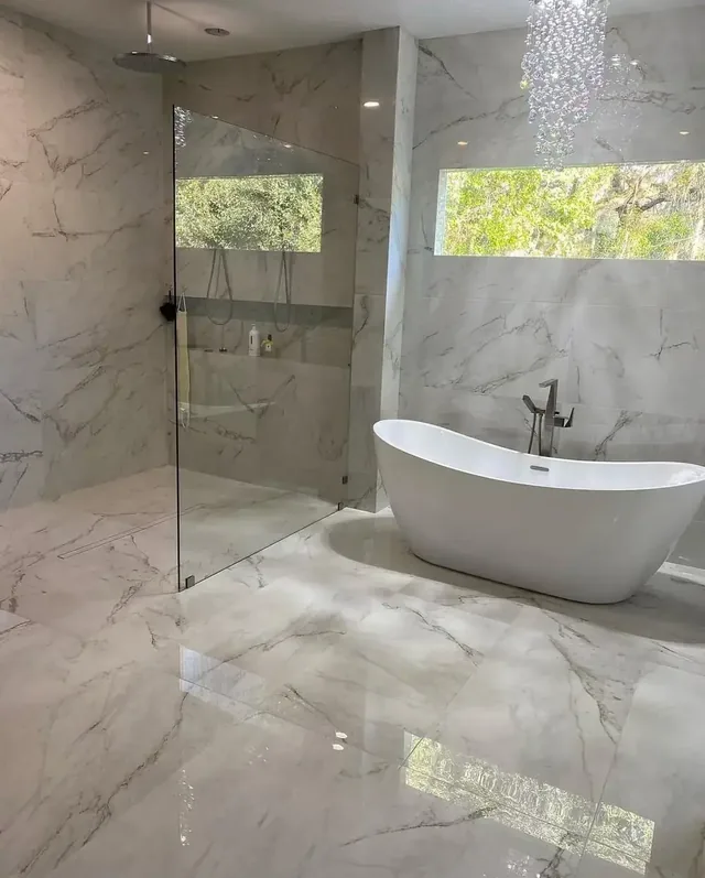 Finished bathroom with marble-tiled walk-in shower, freestanding tub, and crystal chandelier