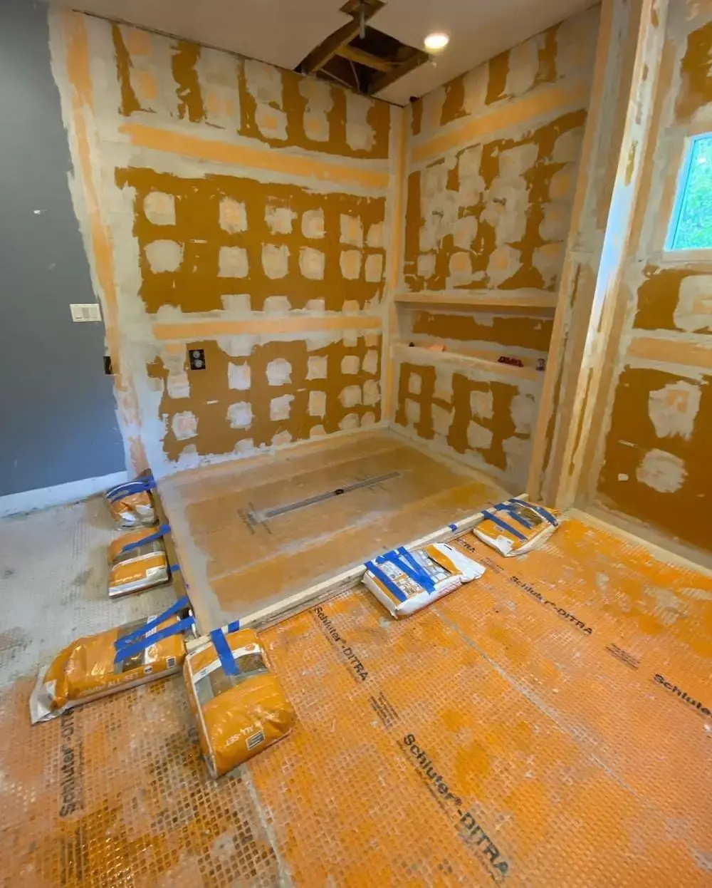 Shower pan and walls waterproofed with Schluter-Ditra membrane before tile