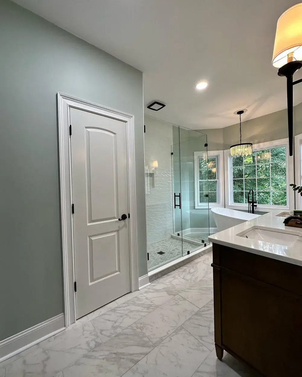 New frameless glass shower with white subway tile and marble-look floor tile