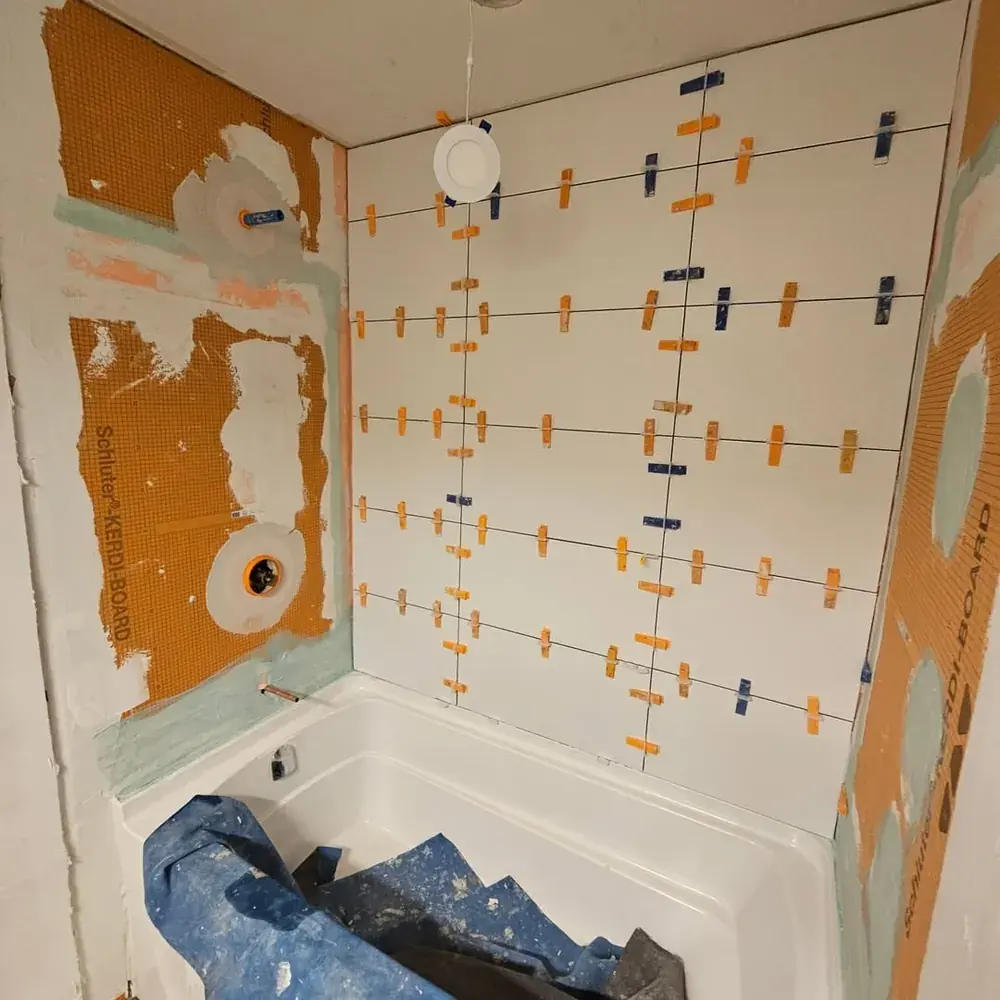 New white tile being set with leveling clips over the waterproofed walls