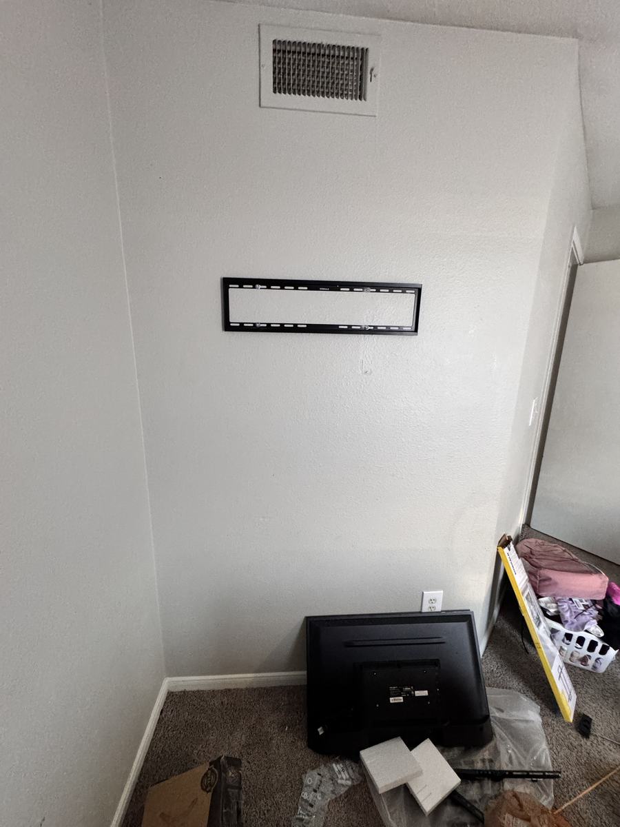 TV wall mount bracket installed with TV waiting on the floor, before final hang