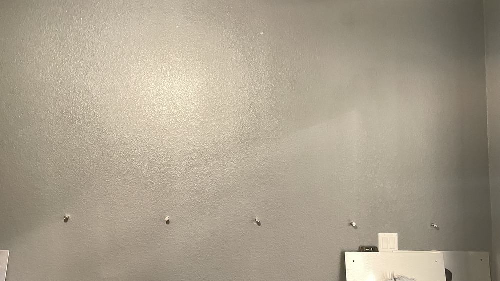 Blank hallway wall with mounting anchors pre-placed in an even row, before art panel install