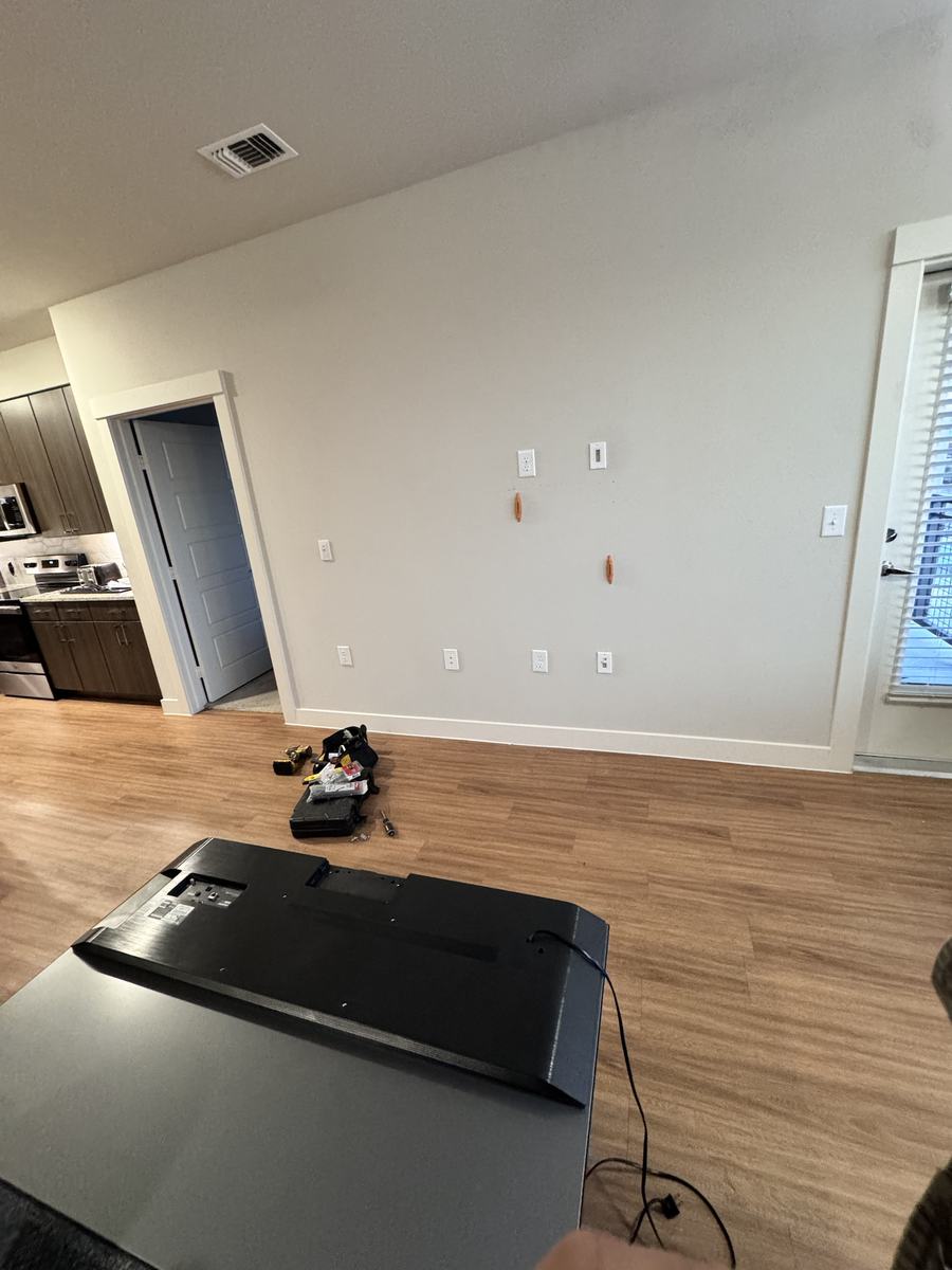 Empty wall with outlets prepped and TV waiting to be mounted, before install