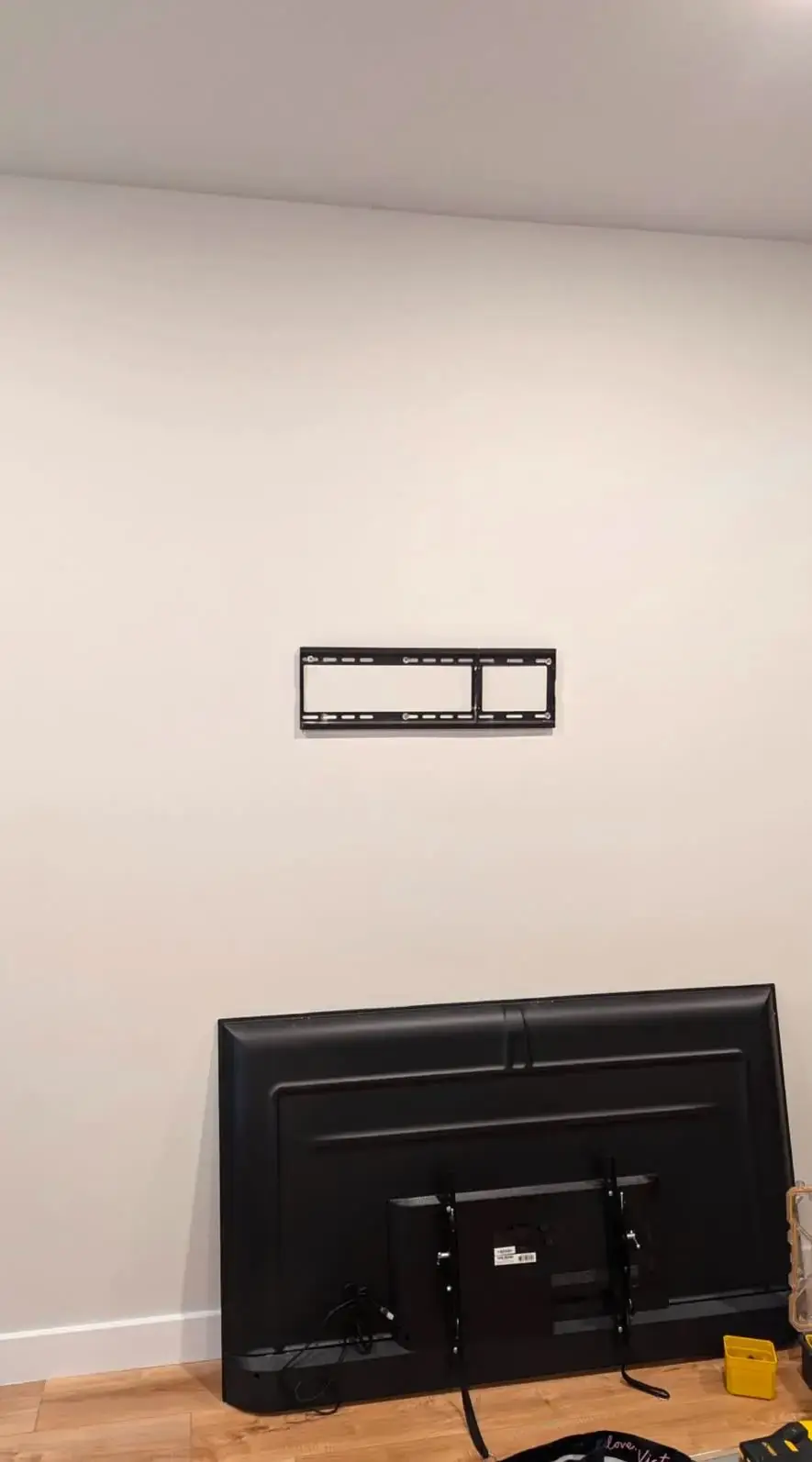 TV wall mount bracket installed and leveled with the TV waiting on the floor below, before final hang