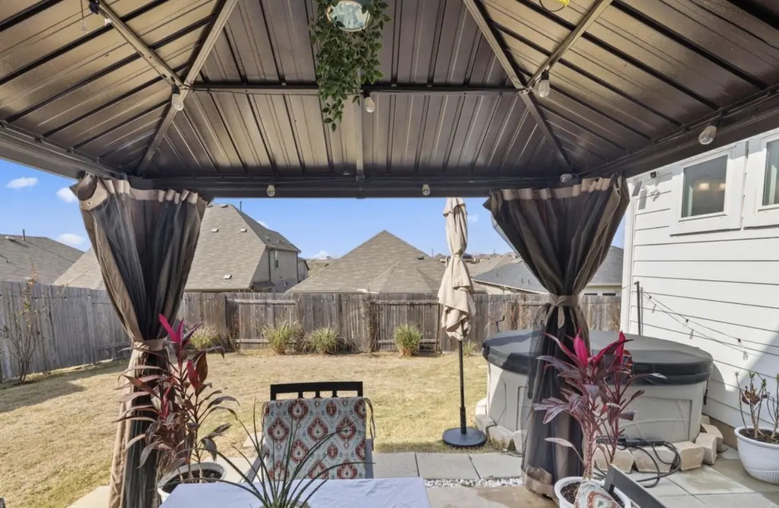 Covered backyard patio with a gazebo and hot tub