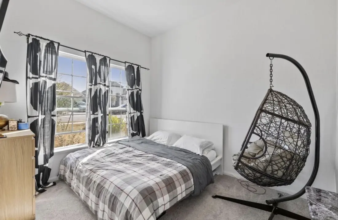 Bedroom with a hanging egg chair by the window