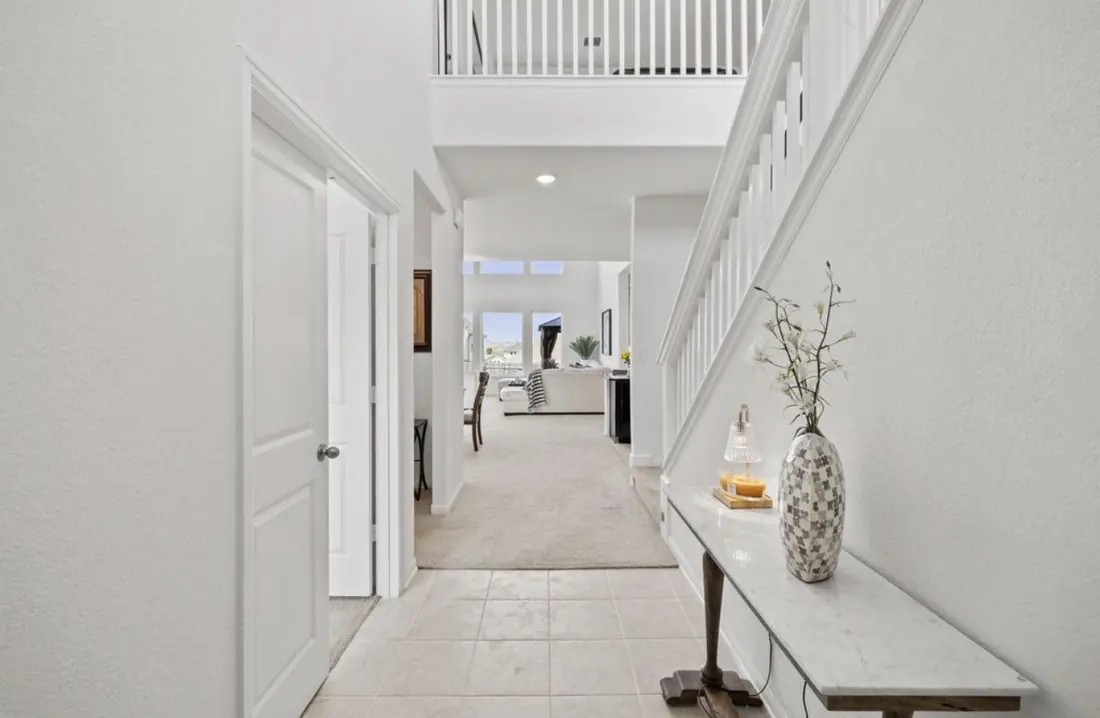 Hallway with remodeled tile flooring leading past the staircase into the living area