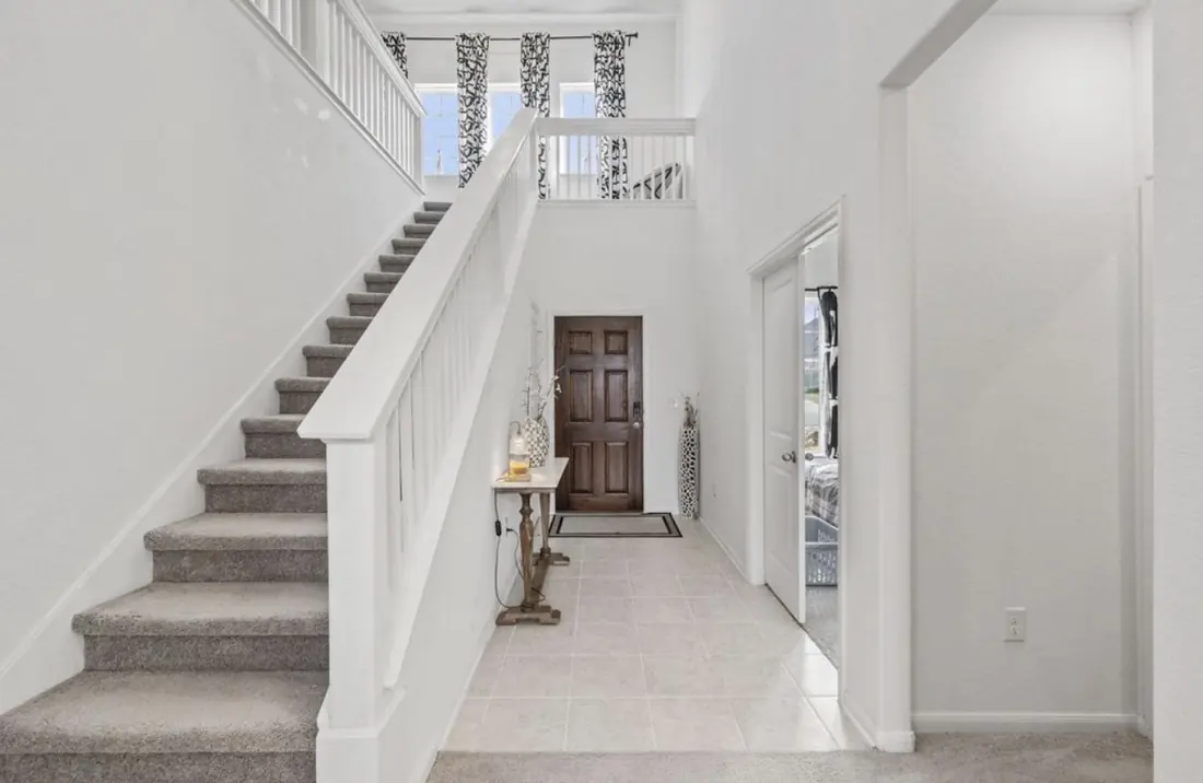 Two-story entry foyer with a carpeted staircase