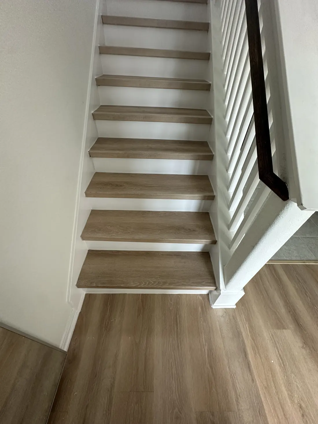 Staircase with new wood-look flooring on the treads and white risers
