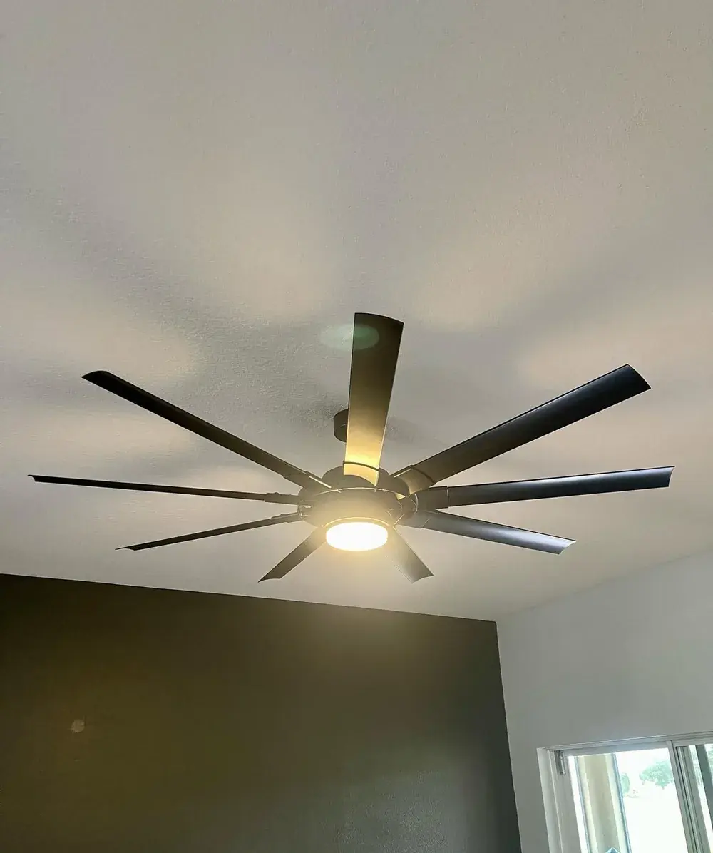 Matte black 8-blade ceiling fan with integrated light installed in a bedroom with a dark accent wall