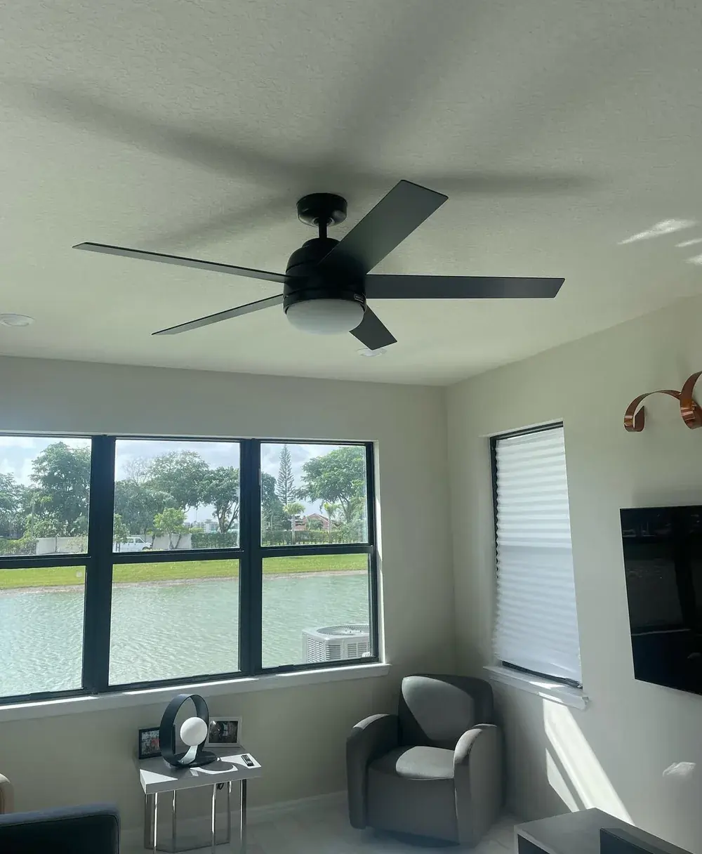 Same living room with a new black 5-blade ceiling fan and light installed