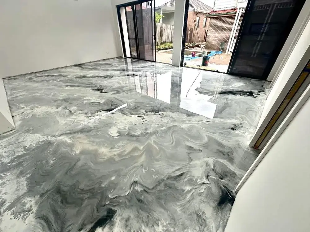 Glossy metallic epoxy floor coating reflecting light near sliding patio doors