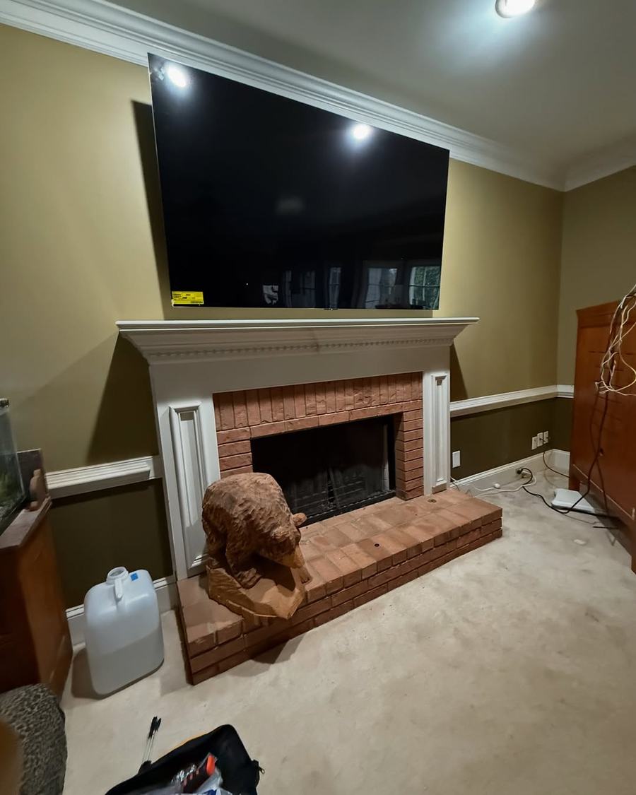TV mounted above a brick fireplace in a classic den
