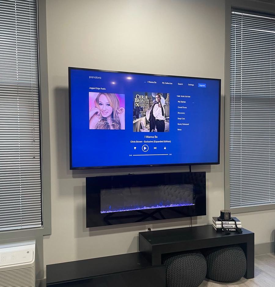 TV mounted above a floating electric fireplace, wires hidden and powered on