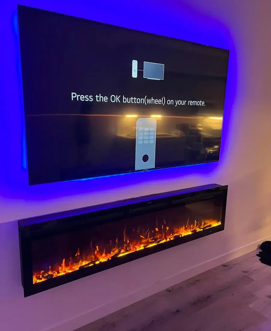 TV mounted above a fireplace insert with accent lighting around the frame