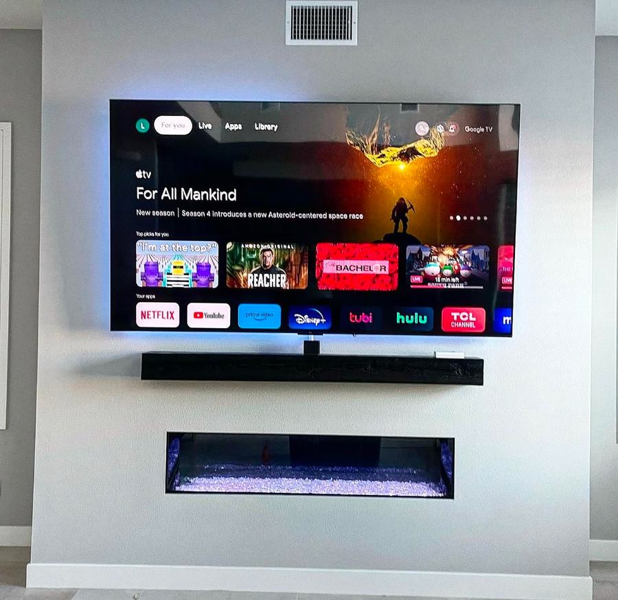 TV and soundbar mounted above a built-in fireplace niche on a media wall