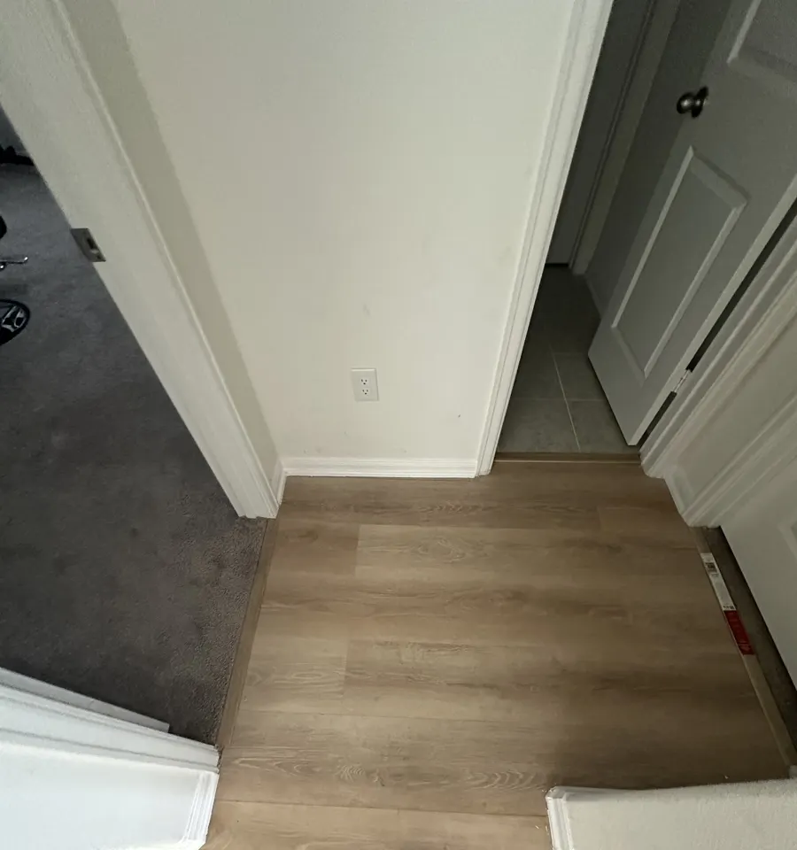 Upstairs landing where the new floor meets carpet and tile with transition strips