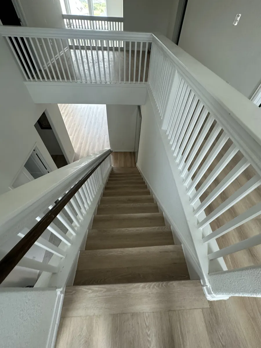 The same staircase and landing finished with wood-look vinyl plank treads and flooring