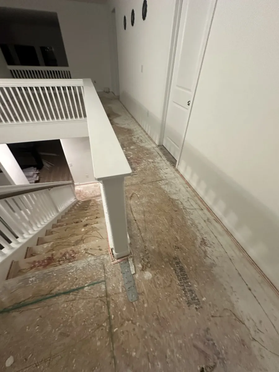 Staircase and landing with the carpet torn out down to the plywood subfloor
