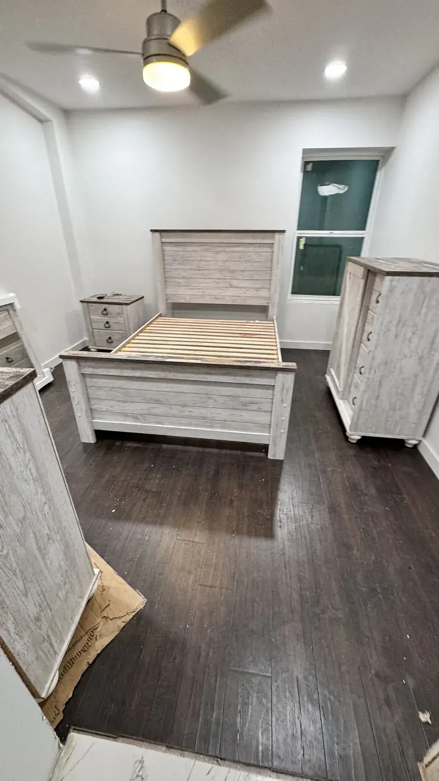 Assembled bed frame, nightstand, and tall cabinet set up in a bedroom