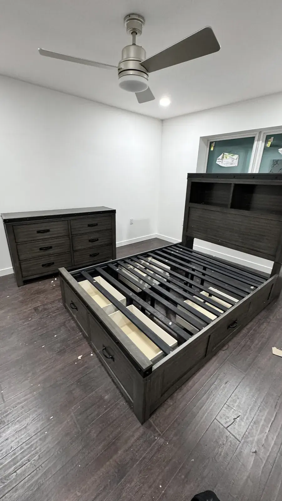 Assembled storage bed frame with drawers and matching six-drawer dresser in a bedroom