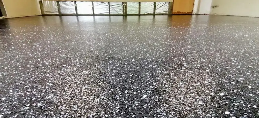 Black and silver flake epoxy garage floor coating in a dimly lit garage