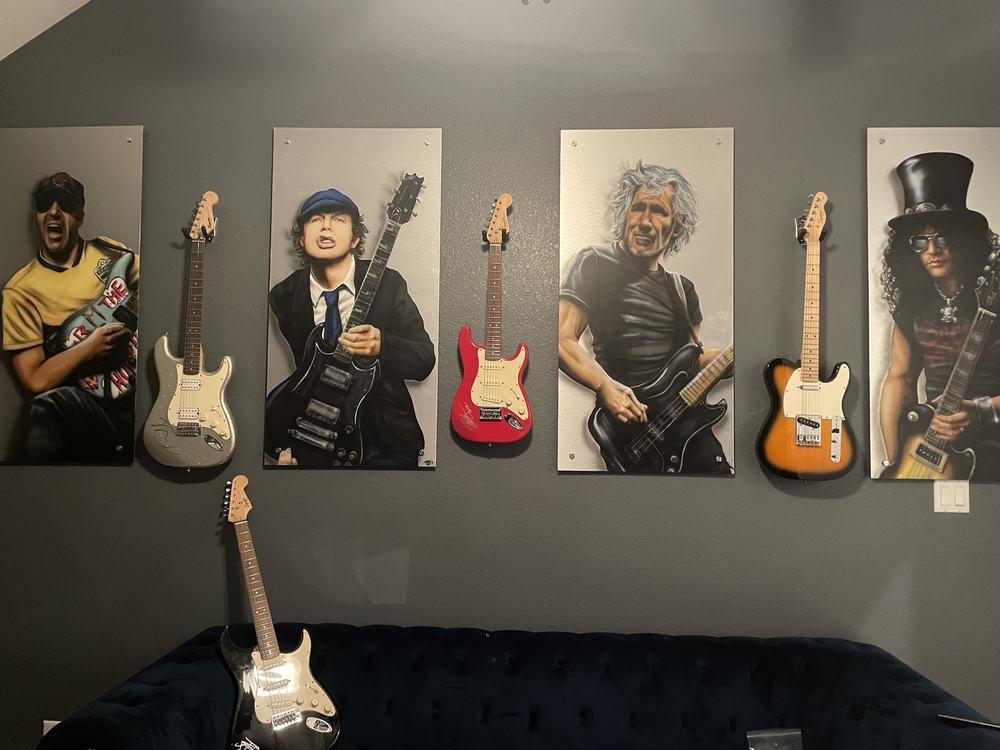 Close-up of guitar wall mounts and printed art panels hung in a tight grid