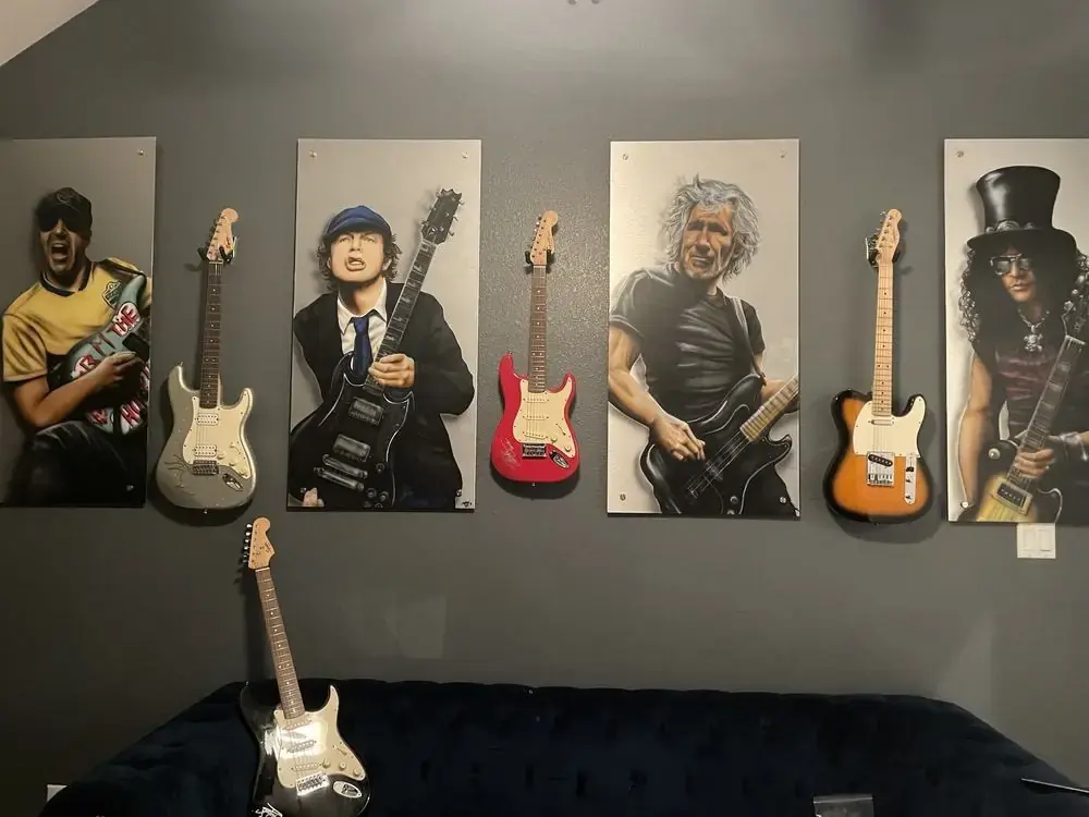 Close-up of guitar wall mounts and printed art panels hung in a tight grid