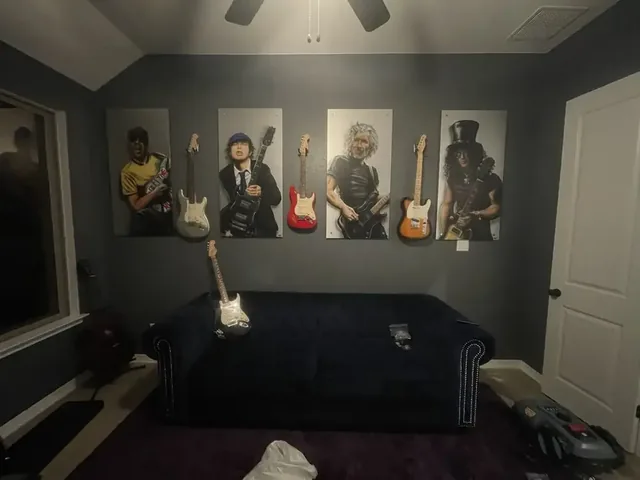 Six wall-mounted guitars and matching art panels installed on a media wall above a couch