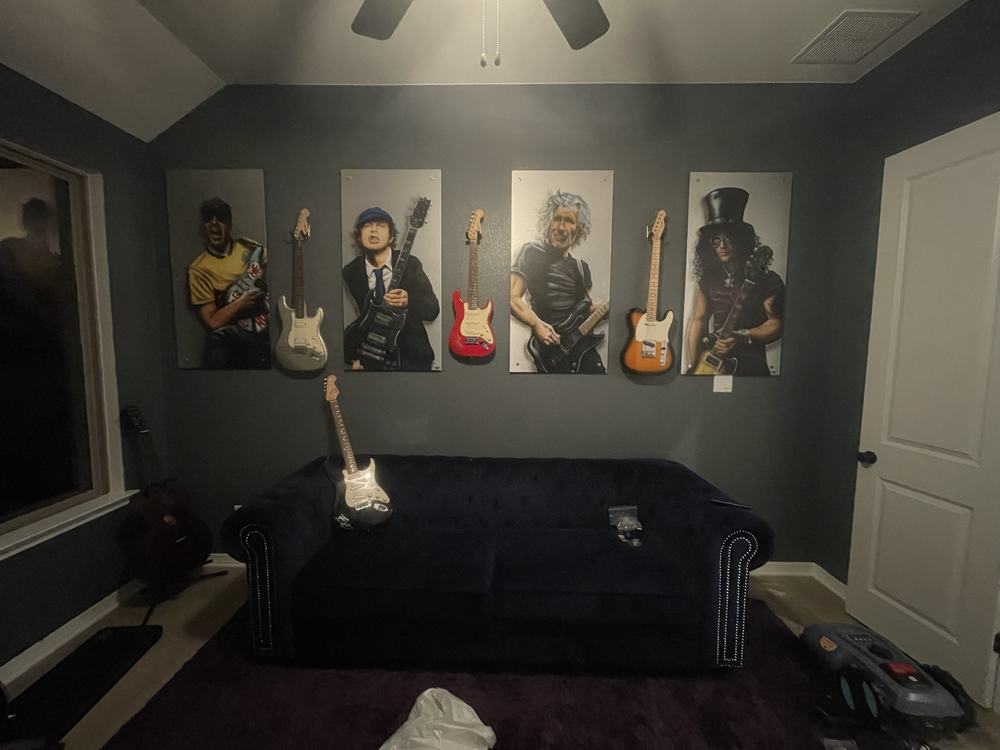 Six wall-mounted guitars and matching art panels installed on a media wall above a couch