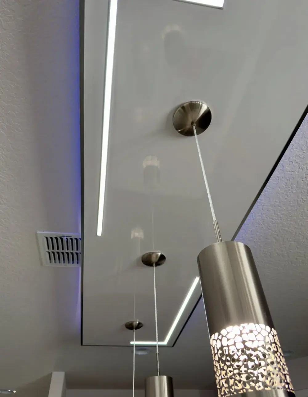 Close-up of pendant lights and recessed LED accent trim on a custom kitchen ceiling feature