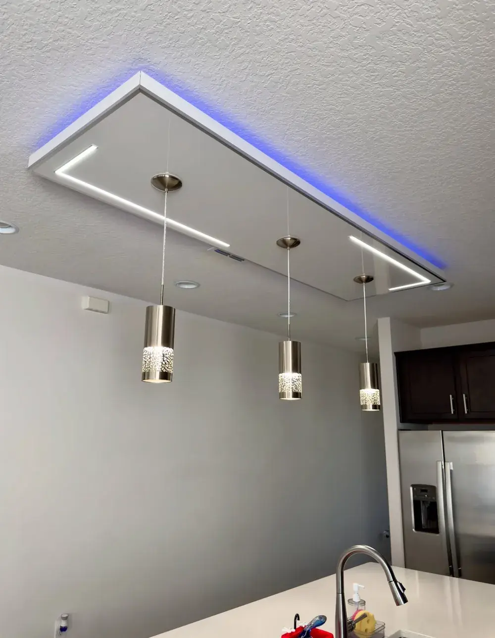 Custom kitchen ceiling light feature with blue LED accent trim and three pendant lights over an island