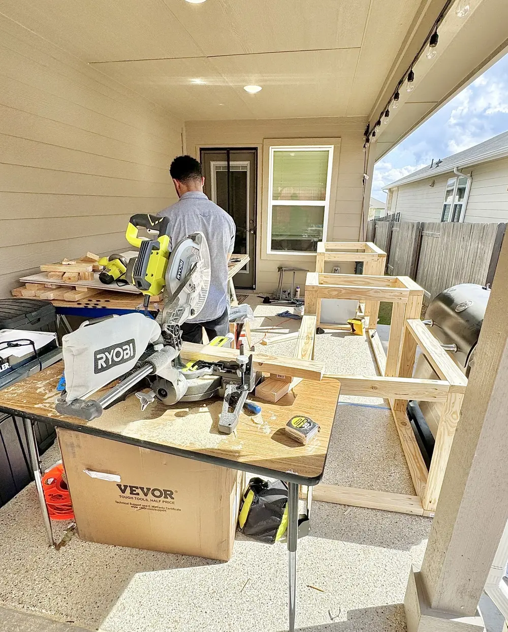 Wood-frame cabinet bases under construction on a covered patio for a custom outdoor kitchen build