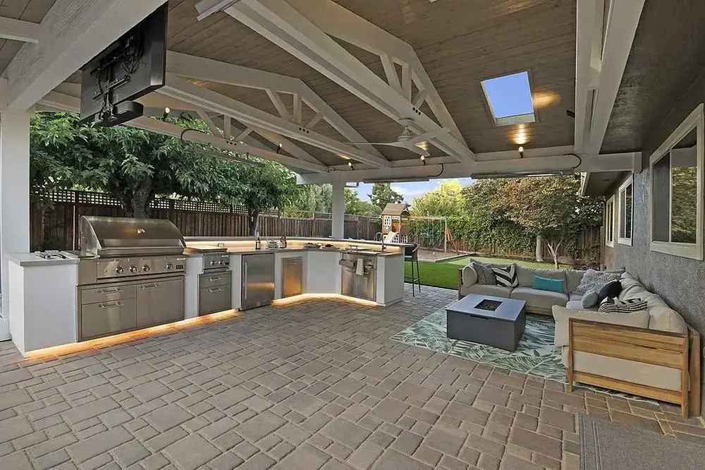 Covered patio outdoor kitchen with mounted TV and built-in seating area
