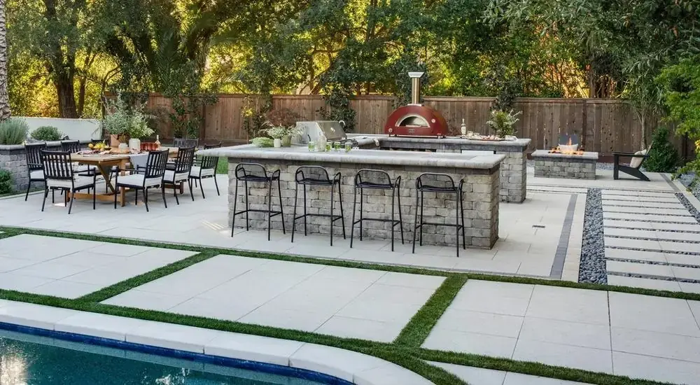 Poolside stone outdoor kitchen with pizza oven and dining and fire pit areas